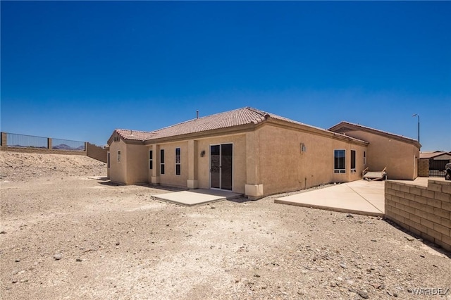 rear view of house featuring a tile roof, a patio area, fence, and stucco siding