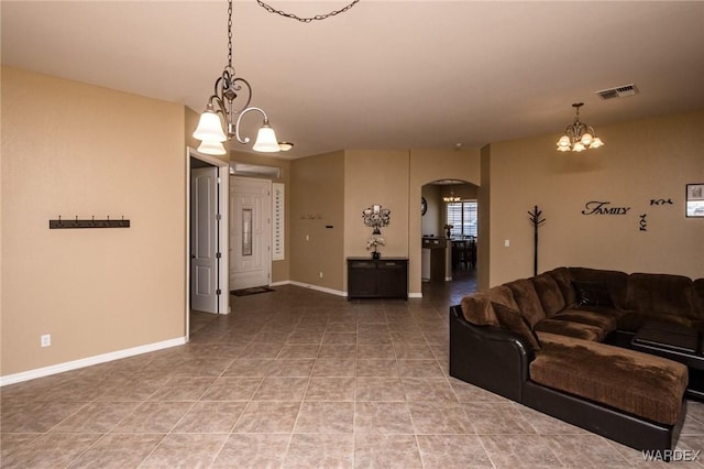 tiled living room featuring arched walkways, visible vents, a notable chandelier, and baseboards