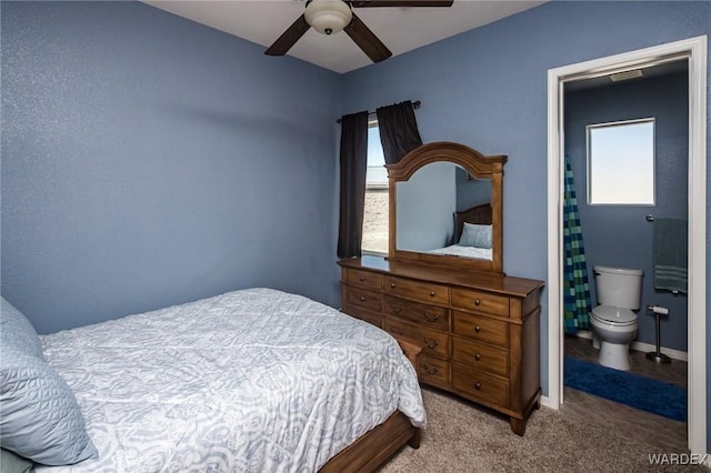 carpeted bedroom featuring ensuite bath, a ceiling fan, and baseboards