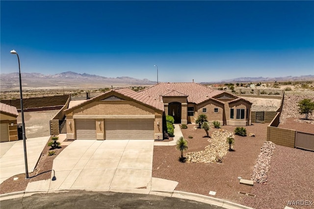 view of front facade with a tile roof, stucco siding, concrete driveway, a mountain view, and a garage