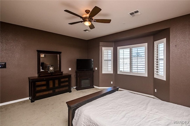 carpeted bedroom featuring baseboards, visible vents, a ceiling fan, and a glass covered fireplace