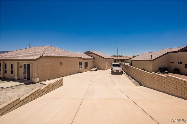 view of property exterior with a patio area, a tile roof, fence, and stucco siding