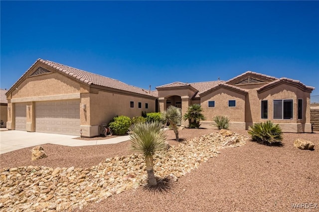 mediterranean / spanish house with an attached garage, a tiled roof, concrete driveway, and stucco siding