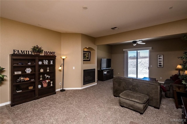 carpeted living room with baseboards, a fireplace, visible vents, and a ceiling fan