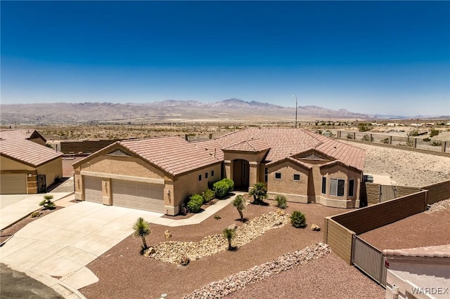 view of front of home featuring concrete driveway, a tiled roof, fence, a mountain view, and stucco siding