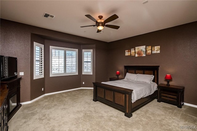 bedroom featuring baseboards, visible vents, light colored carpet, and a glass covered fireplace