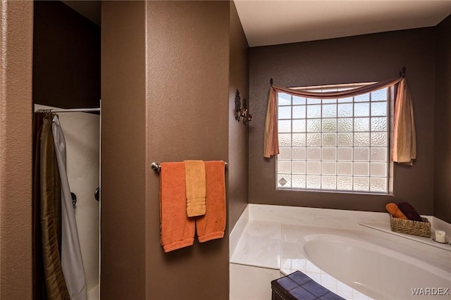 full bathroom with a textured wall, plenty of natural light, and a bath