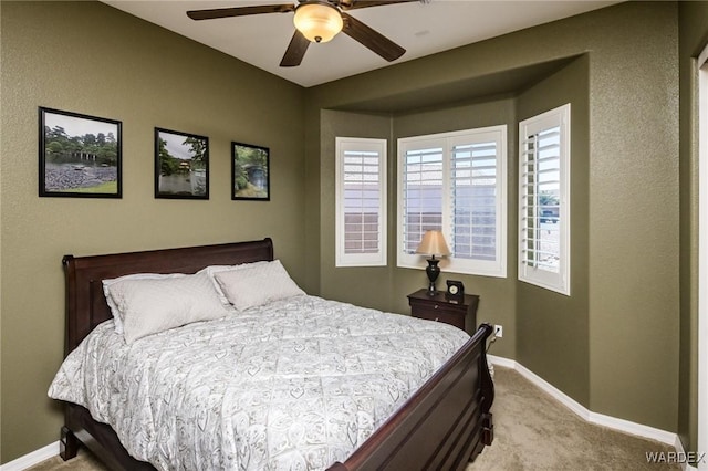 bedroom featuring a ceiling fan, light colored carpet, and baseboards