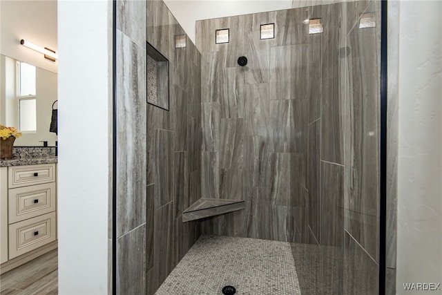 full bathroom with tiled shower and vanity