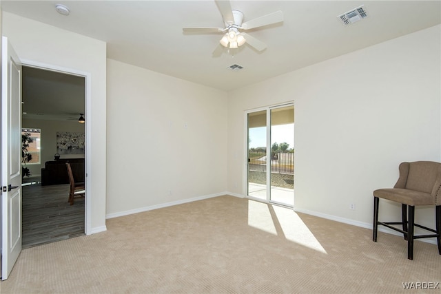 interior space with baseboards, a ceiling fan, visible vents, and light colored carpet