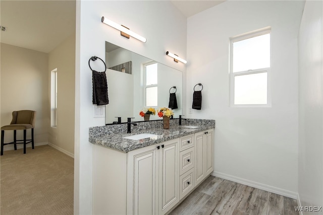 bathroom with a sink, baseboards, and double vanity