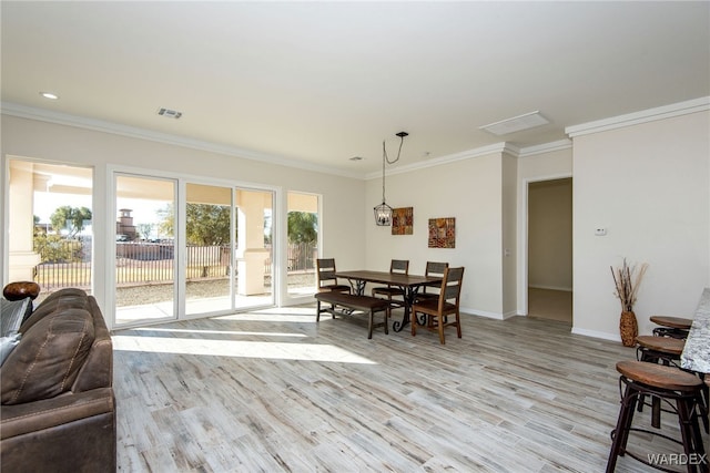 dining space with light wood finished floors, visible vents, baseboards, and crown molding