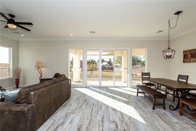 living room featuring a wealth of natural light, crown molding, and light wood-style flooring