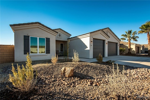 ranch-style home with an attached garage, fence, concrete driveway, and stucco siding