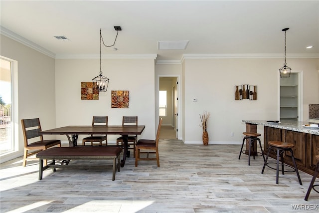 dining area with ornamental molding, visible vents, light wood-style floors, and baseboards