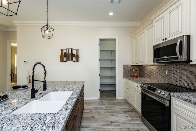 kitchen featuring appliances with stainless steel finishes, light stone counters, a sink, and decorative light fixtures