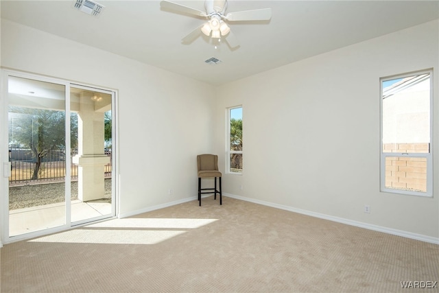 unfurnished room featuring a ceiling fan, light colored carpet, visible vents, and baseboards