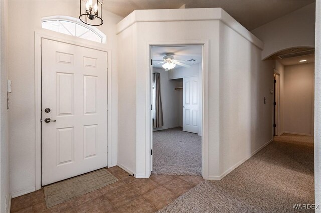 foyer with arched walkways, light carpet, baseboards, and an inviting chandelier