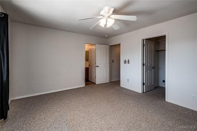 unfurnished bedroom with carpet, a spacious closet, baseboards, and a ceiling fan