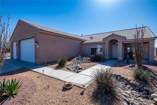 view of front of property with driveway, a tiled roof, an attached garage, and stucco siding