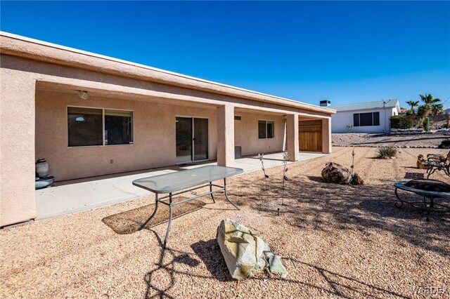 back of house with an outdoor fire pit, a patio area, and stucco siding