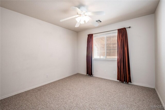 carpeted spare room featuring visible vents, ceiling fan, and baseboards