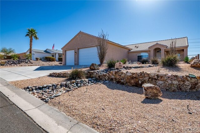 view of front facade featuring concrete driveway, an attached garage, a tiled roof, and stucco siding