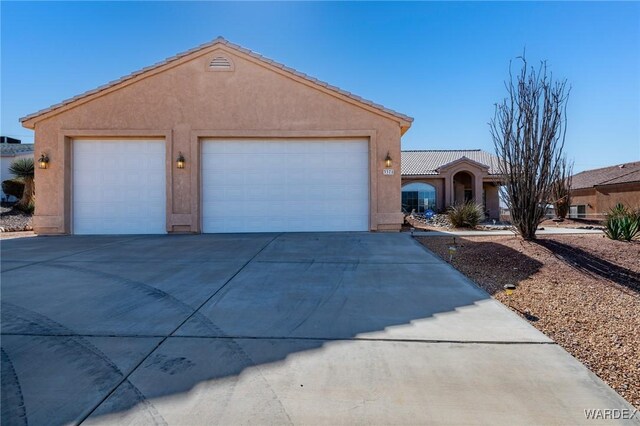 view of front facade with a garage, concrete driveway, a tile roof, and stucco siding