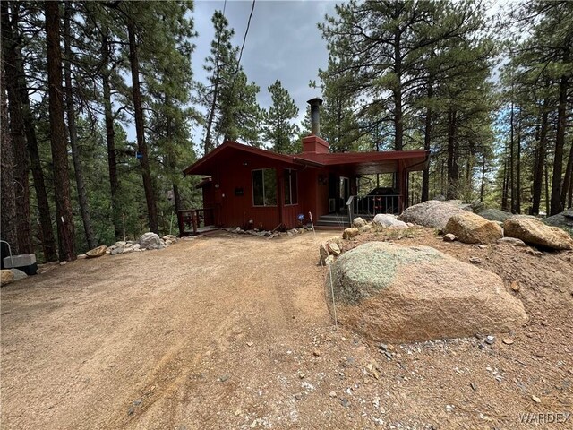 view of side of property featuring a carport, driveway, and a chimney