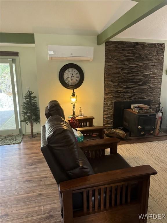 living room featuring beamed ceiling, an AC wall unit, and wood finished floors