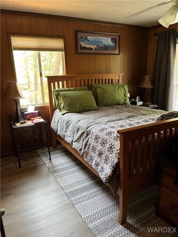 bedroom featuring light wood-style flooring and wooden walls