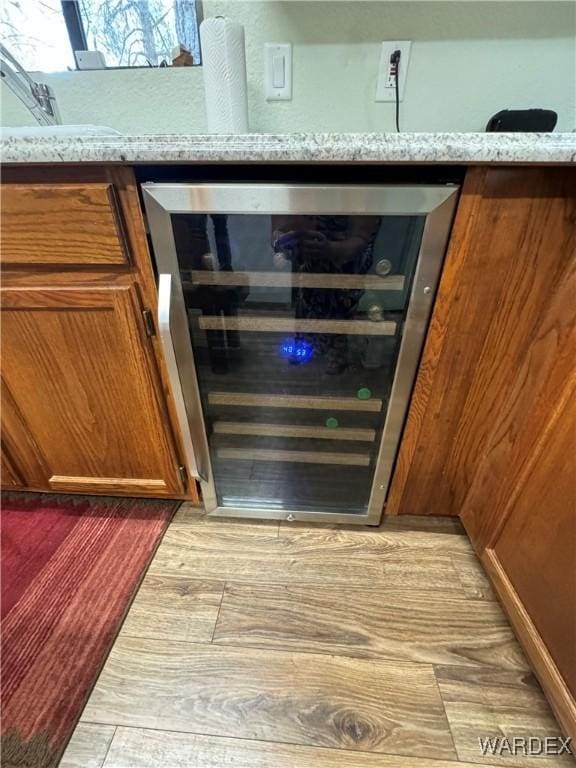 room details featuring brown cabinetry, wine cooler, and light stone counters