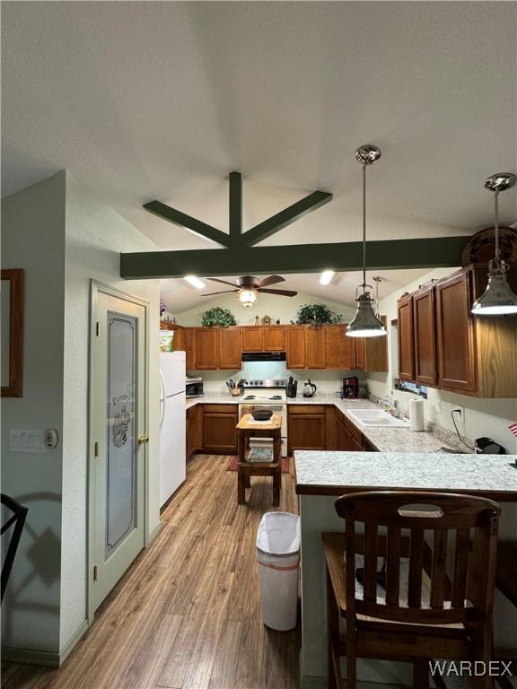 kitchen featuring a peninsula, white appliances, a sink, light countertops, and decorative light fixtures