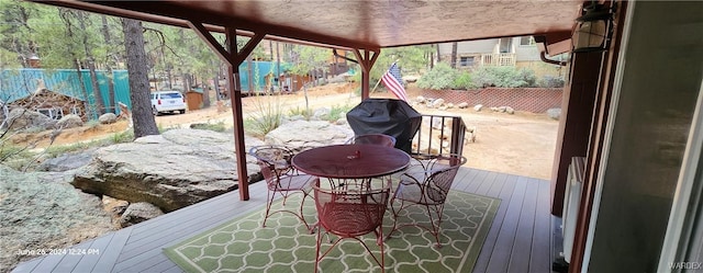 wooden deck featuring outdoor dining area, fence, and a grill