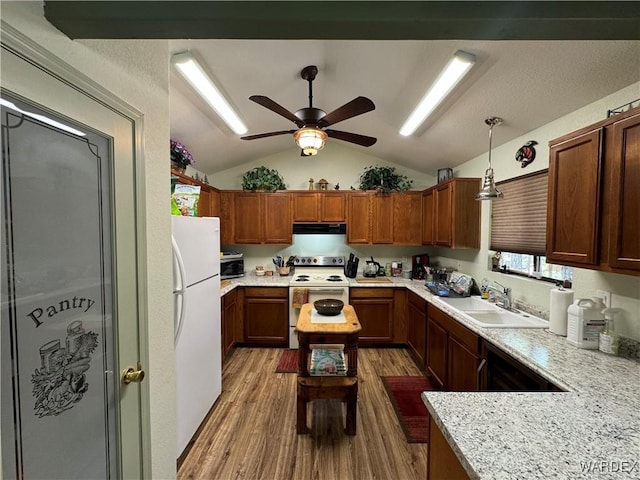 kitchen with hanging light fixtures, vaulted ceiling, a sink, wood finished floors, and white appliances