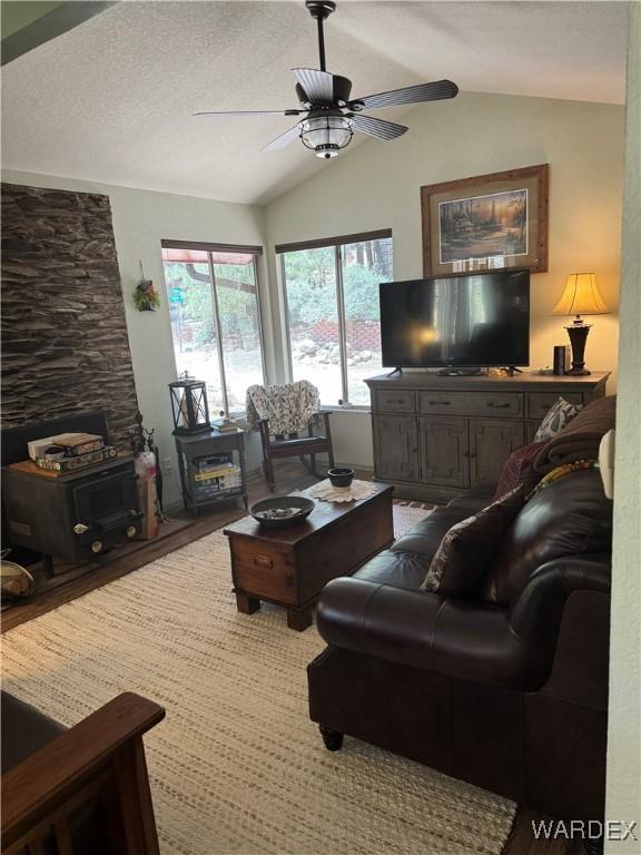 living room with lofted ceiling, a textured ceiling, and a ceiling fan