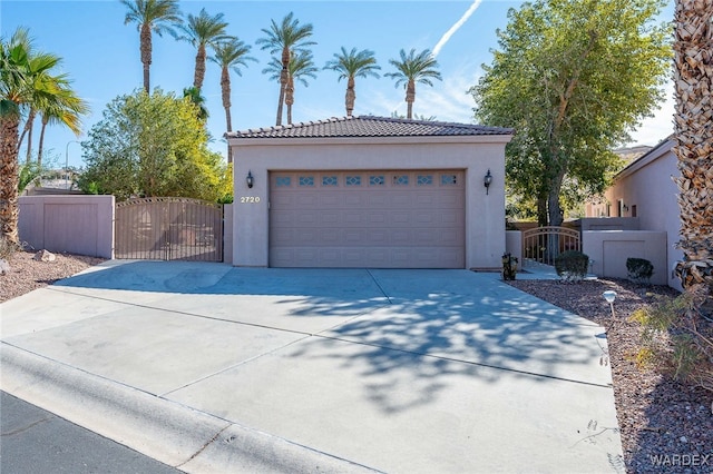 garage featuring a gate, fence, and concrete driveway