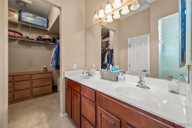 bathroom with a walk in closet, tile patterned flooring, a sink, and double vanity