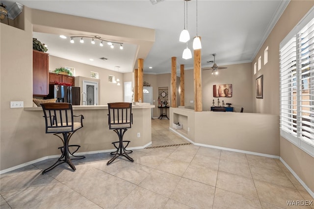 kitchen with light tile patterned floors, a peninsula, stainless steel fridge, and crown molding