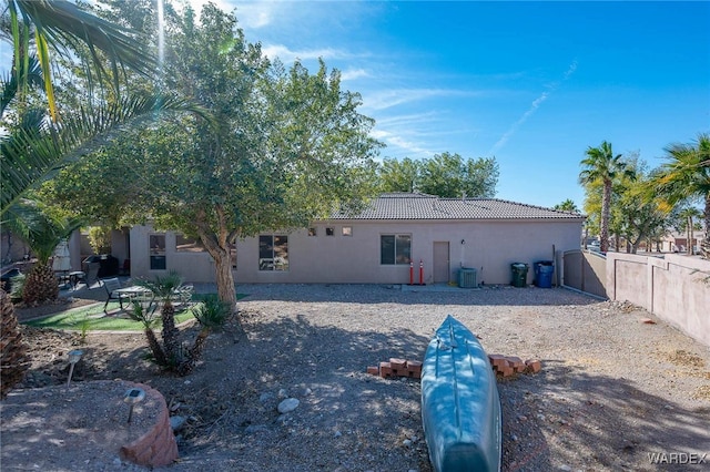 rear view of house featuring central air condition unit, a tile roof, fence, and stucco siding