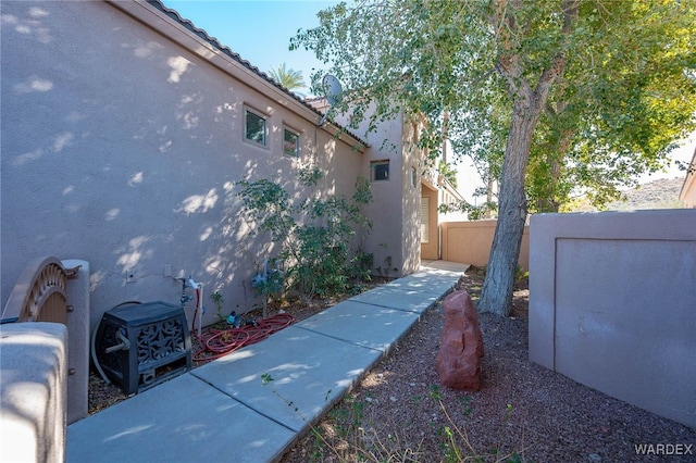 exterior space with a tiled roof, fence, and stucco siding