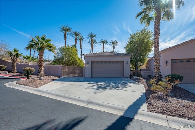 view of front of property with concrete driveway, a tile roof, a gate, fence, and stucco siding