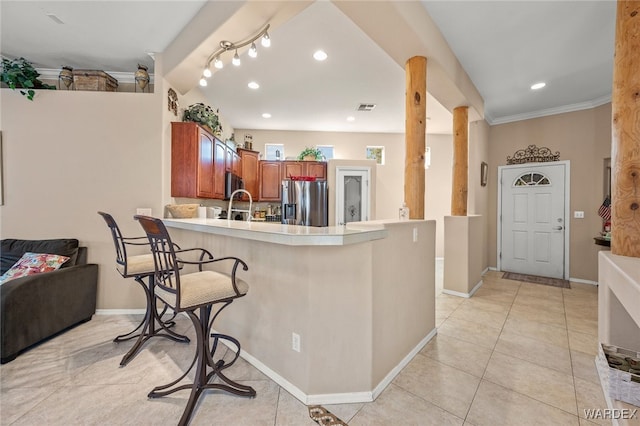 kitchen with stainless steel fridge, visible vents, a kitchen breakfast bar, a peninsula, and light countertops