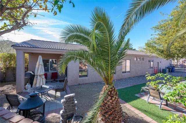 exterior space featuring a patio, central air condition unit, a tile roof, and stucco siding