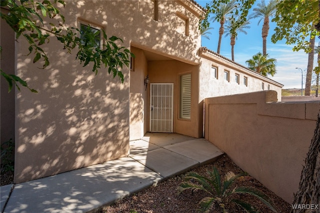 doorway to property with a patio, fence, and stucco siding