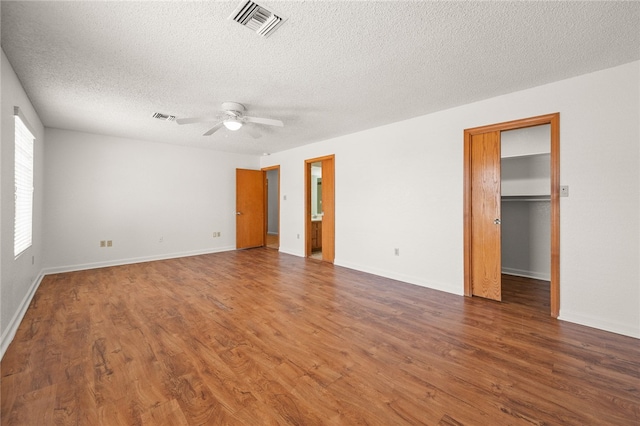 2218 Family Cir, Bullhead City, AZ 86442 - unfurnished bedroom with a textured ceiling, wood finished floors, a spacious closet, ceiling fan, and ensuite bathroom