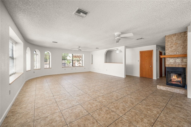 2218 Family Cir, Bullhead City, AZ 86442 - unfurnished living room featuring a ceiling fan, light tile patterned flooring, a textured ceiling, and a tiled fireplace