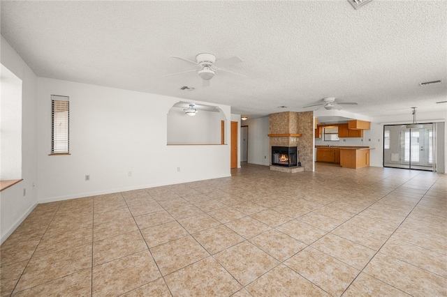 2218 Family Cir, Bullhead City, AZ 86442 - unfurnished living room featuring a ceiling fan, a textured ceiling, a large fireplace, and light tile patterned flooring