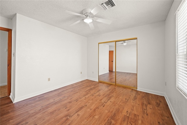 2218 Family Cir, Bullhead City, AZ 86442 - unfurnished bedroom featuring light wood finished floors, multiple windows, a textured ceiling, a closet, and a ceiling fan