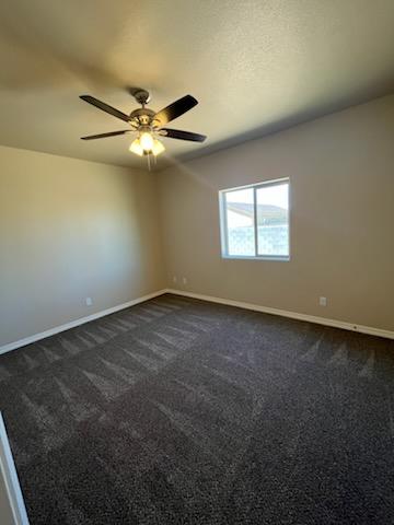 3521 E Lum Ave, Kingman, AZ 86409 - spare room featuring baseboards, dark carpet, and a ceiling fan